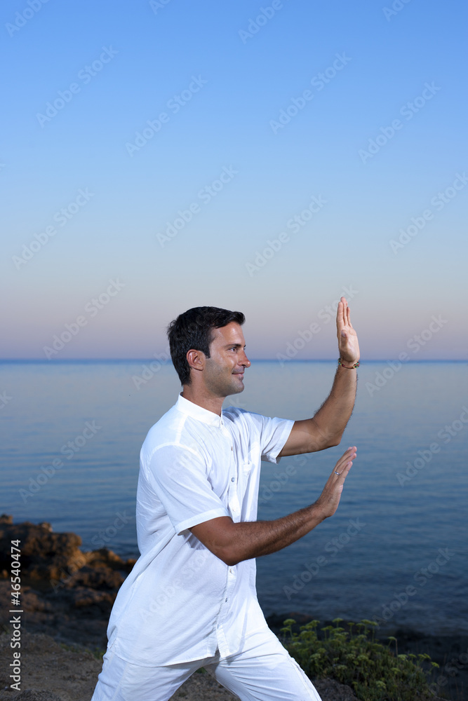 Handsome man on the beach meditating - Tai chi Handsome man on the beach meditating - Tai chi