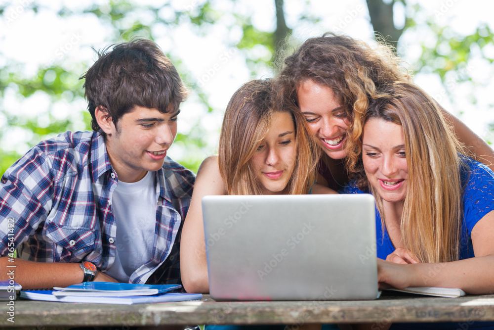 Group of Teenage Students at Park with Computer and Books Group of Teenage Students at Park with Computer and Books