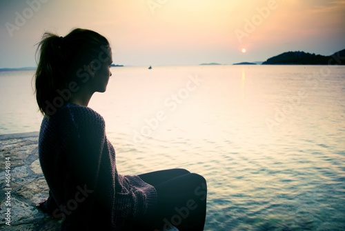 Young woman sitting on the beach at sunset  a symbol of dreams
