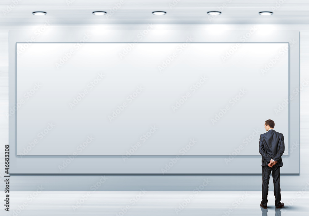 Business person standing near a blank billboard Business person standing near a blank billboard