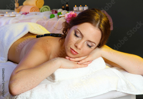 beautiful young woman in spa salon with spa stones