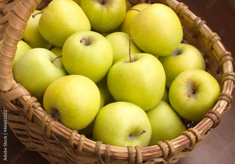 Many ripe apples in brown wicker basket closeup