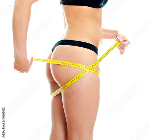 Slim female body with measure tape around hips.