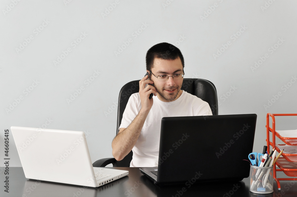 Young businessman working at his desk with two laptops Young businessman working at his desk with two laptops