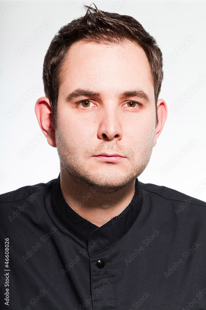 Obraz premium Young male cook with black cooks jacket isolated on white.