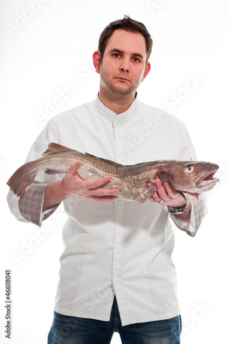 Young male cook with white jacket holding a big fish.