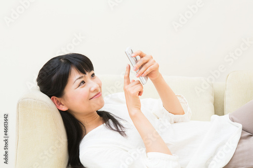 ソファーでスマートフォンを見る女性