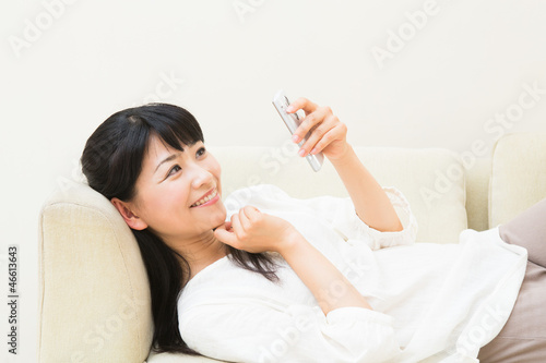 ソファーでスマートフォンを見る女性