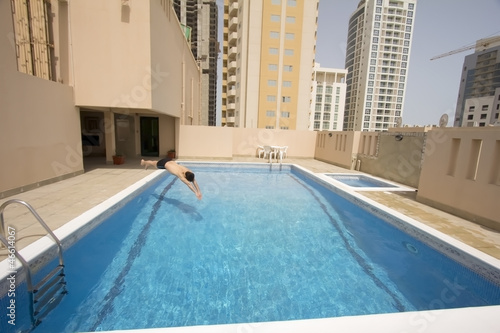 man swim in swimming pool at roof of apartment, bahrain