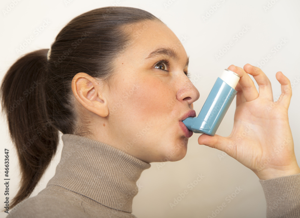 Cute young female using an asthma inhaler Cute young female using an asthma inhaler