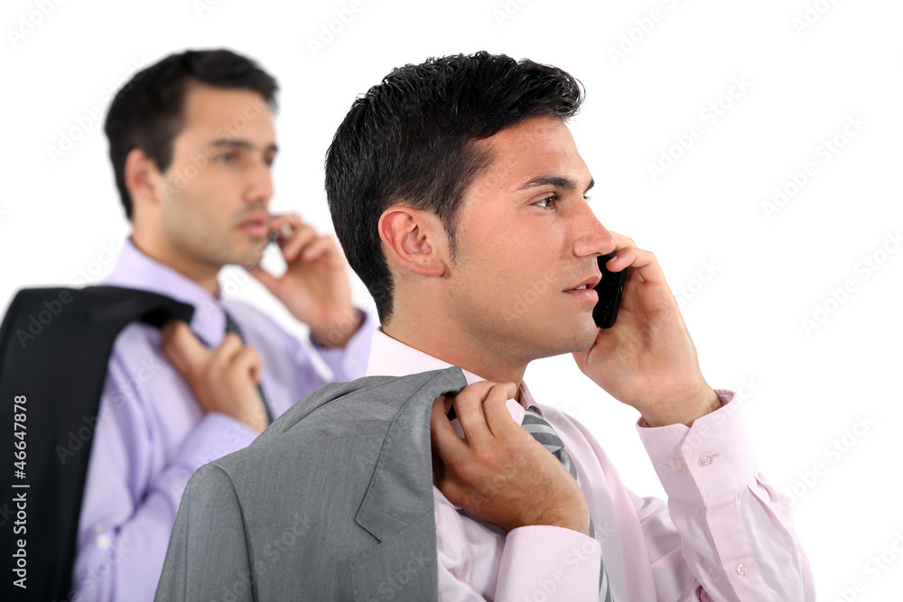 Two businessmen with jackets over shoulders making phone calls Two businessmen with jackets over shoulders making phone calls