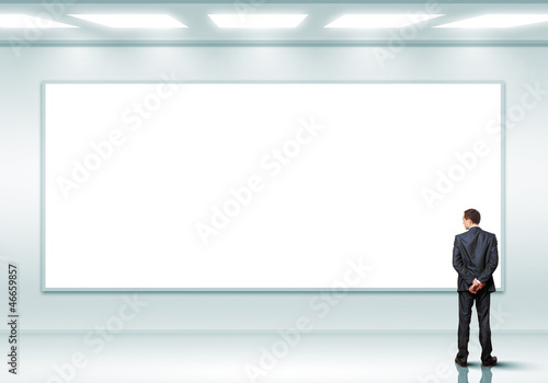 Business person standing near a blank billboard © Sergey Nivens