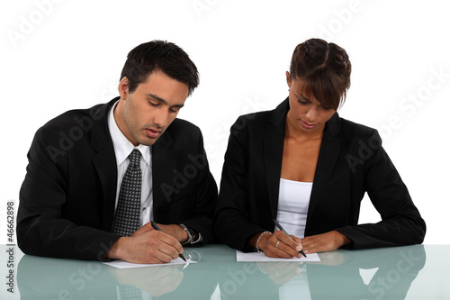 Two businesspeople writing notes