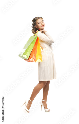 A young woman in a white dress holding shopping bags