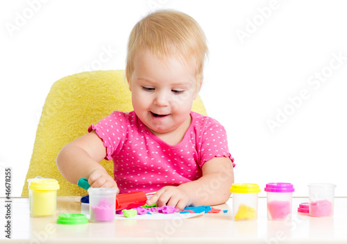 Little kid sitting at table playing with colorful clay