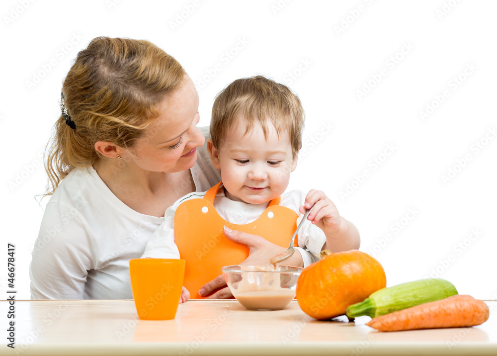 young mother spoon feeding her baby boy isolated on white young mother spoon feeding her baby boy isolated on white