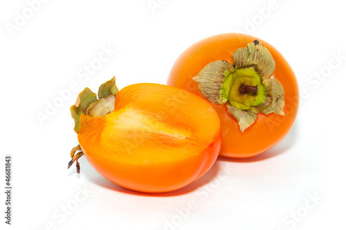 two persimmons, one sliced, close-up on a white background