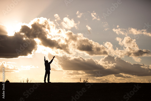 silhouette of a man with arms raised in worship