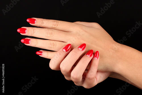 Beautiful female hands with red nails isolated on black