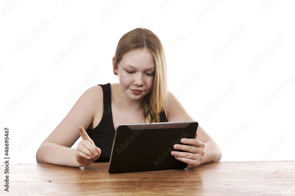 Pretty young girl sitting by table working on tablet computer Pretty young girl sitting by table working on tablet computer