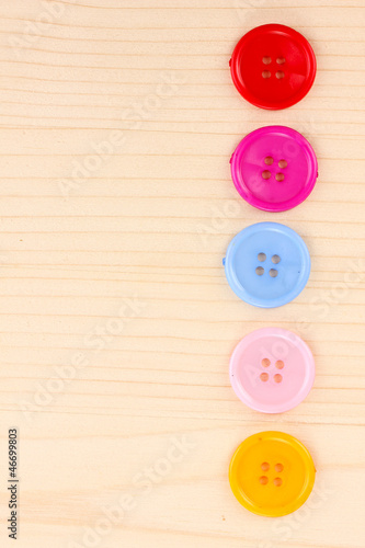 Colorful sewing buttons on wooden background
