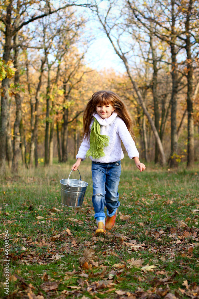 Portrait of a running little girl with a bucket outdoors Portrait of a running little girl with a bucket outdoors