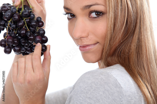 a young woman savouring sensually a grape