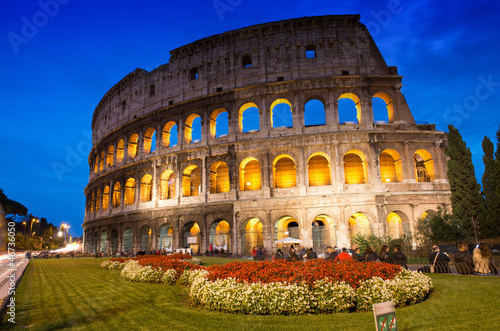 Beautiful view of Colosseum at sunset with flowerbed in foregrou