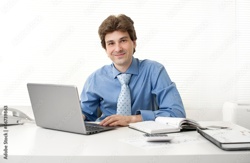 Business man smiling while working in his office Business man smiling while working in his office