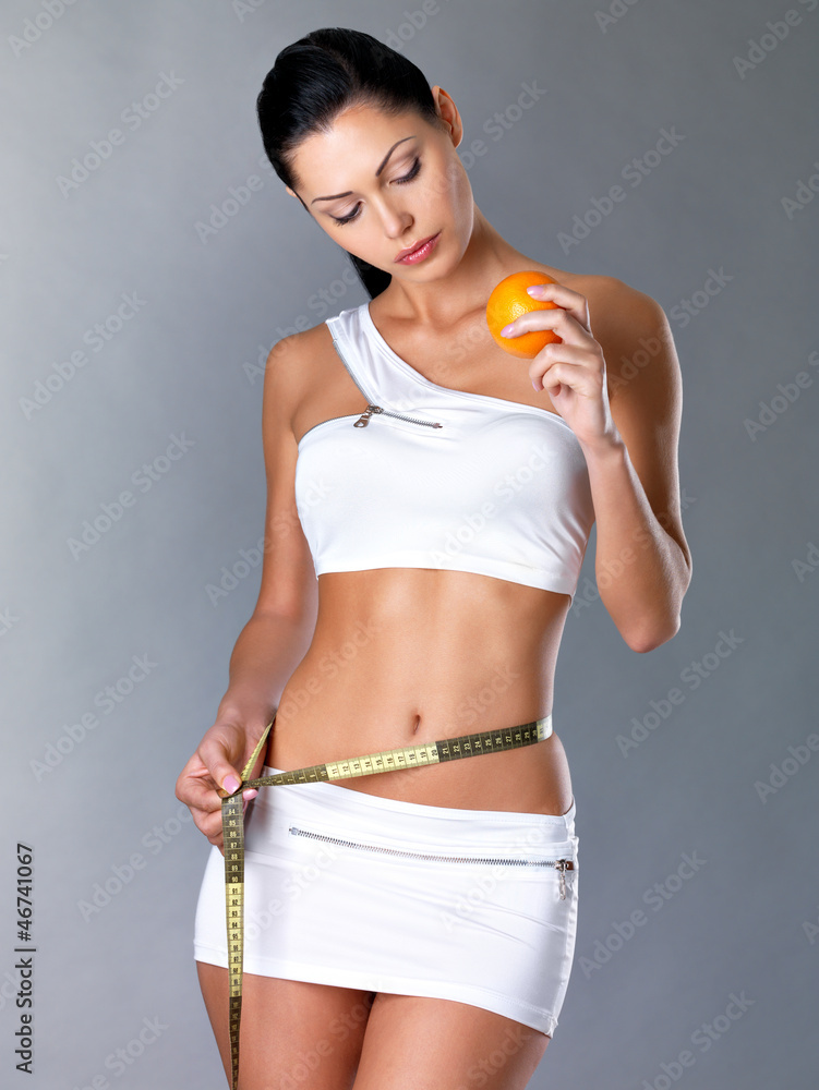 Girl measures figure with a measuring tape and holding orange Girl measures figure with a measuring tape and holding orange