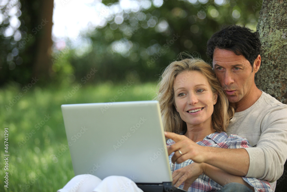 Couple with computer in the garden Couple with computer in the garden