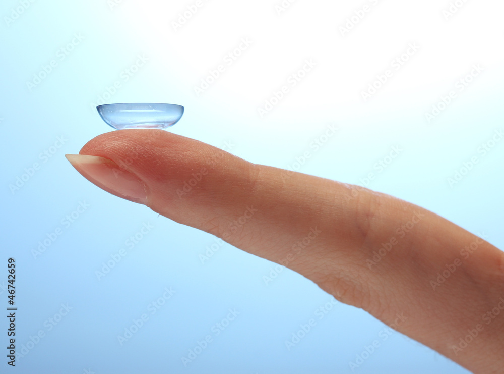 contact lens on finger on blue background contact lens on finger on blue background