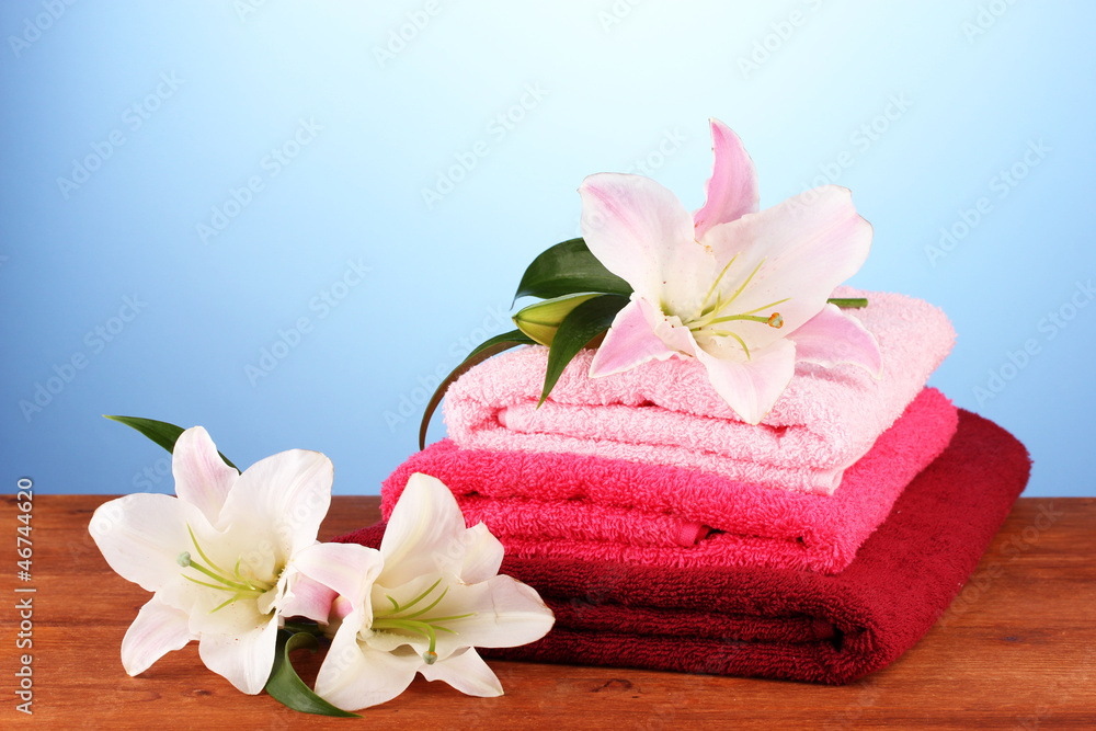 stack of towels with pink lily on blue background. stack of towels with pink lily on blue background.