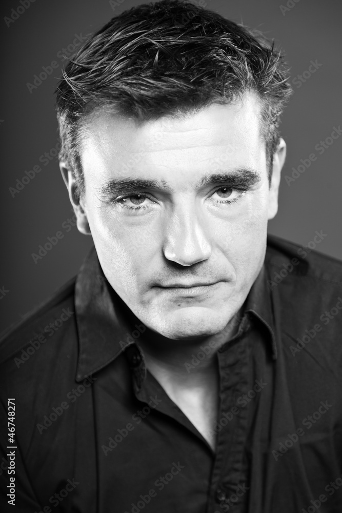 Obraz premium Handsome man with short brown hair. Black and white studio.