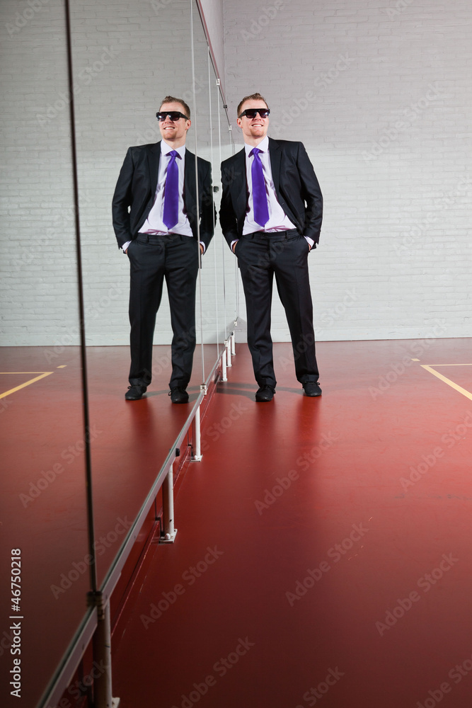 Fototapeta premium Cool looking business man with sunglasses against mirror in gym.