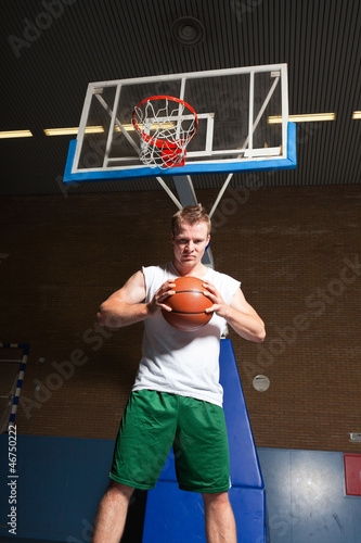 Tough healthy young man playing basketball in gym indoor. © ysbrandcosijn