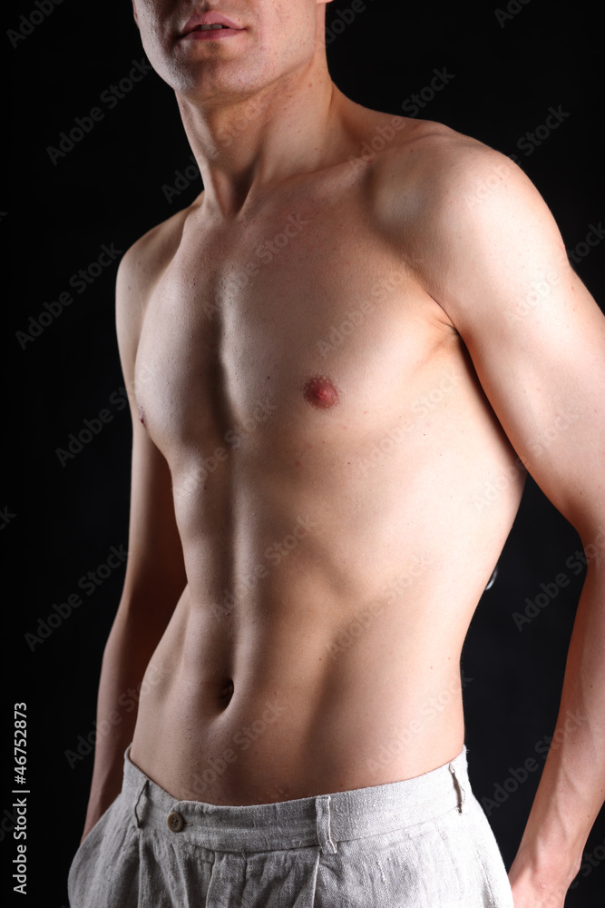 Portrait of a naked muscular man, isolated on black background