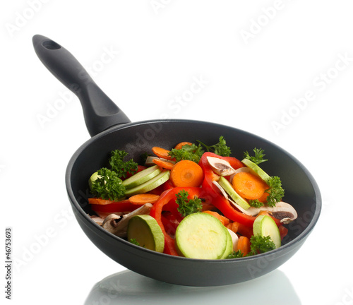 frying pan with vegetables on white
