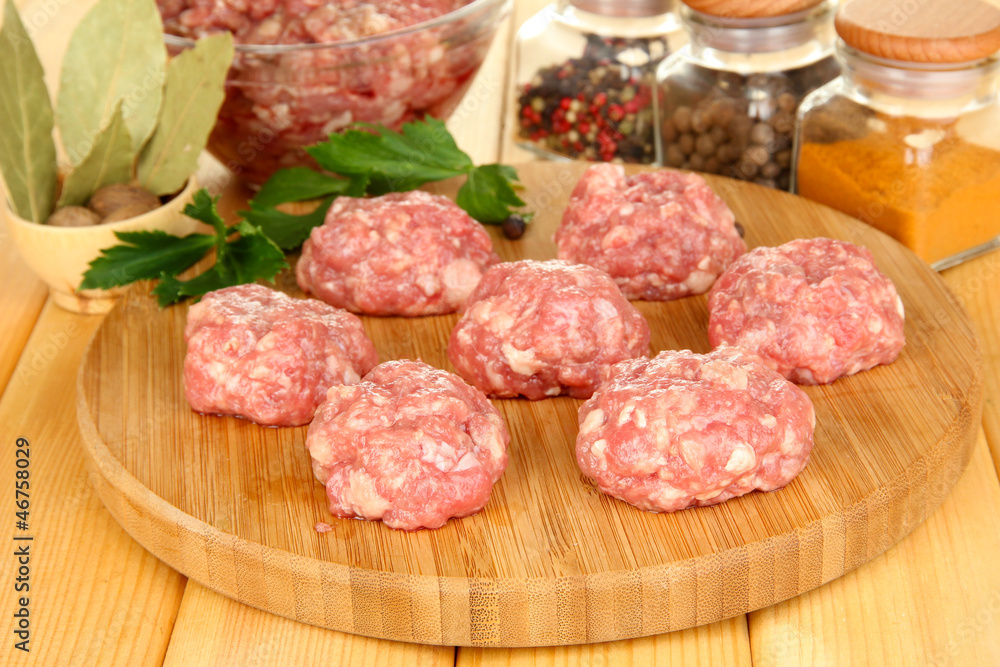 Raw meatballs with spices on wooden table