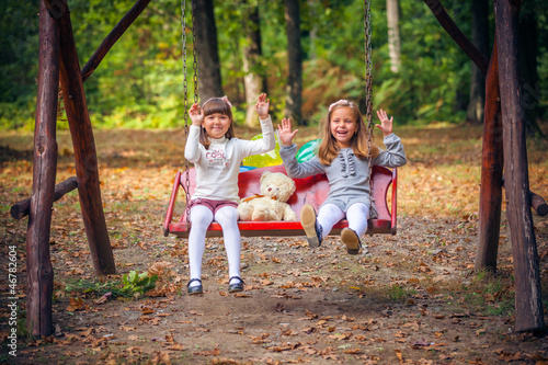 Happy little girlfriends on swing in park © Andriy Petrenko
