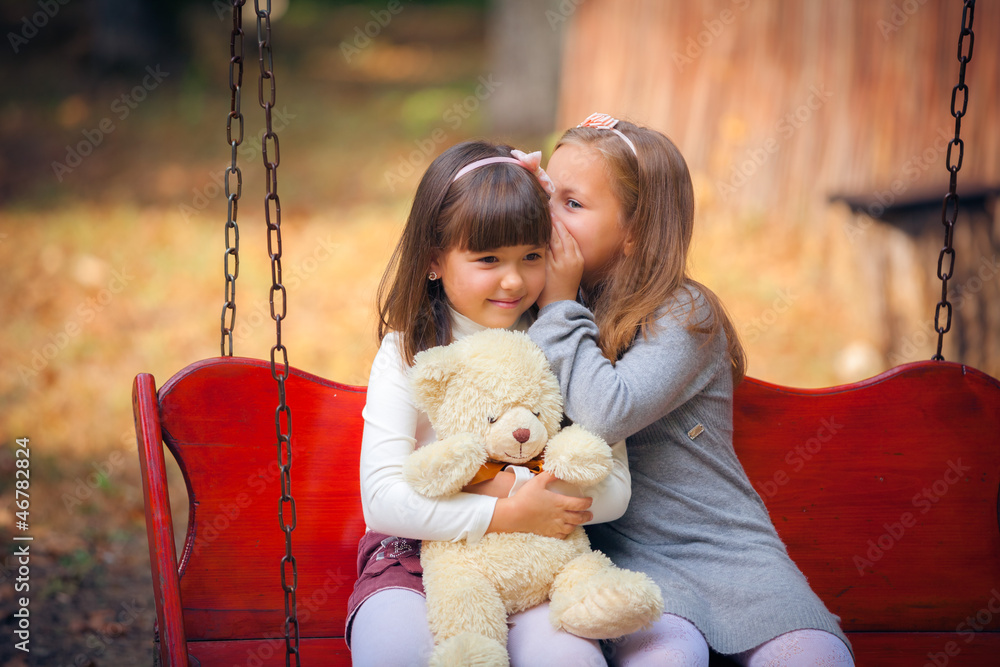 Happy little girlfriends on swing in park Happy little girlfriends on swing in park