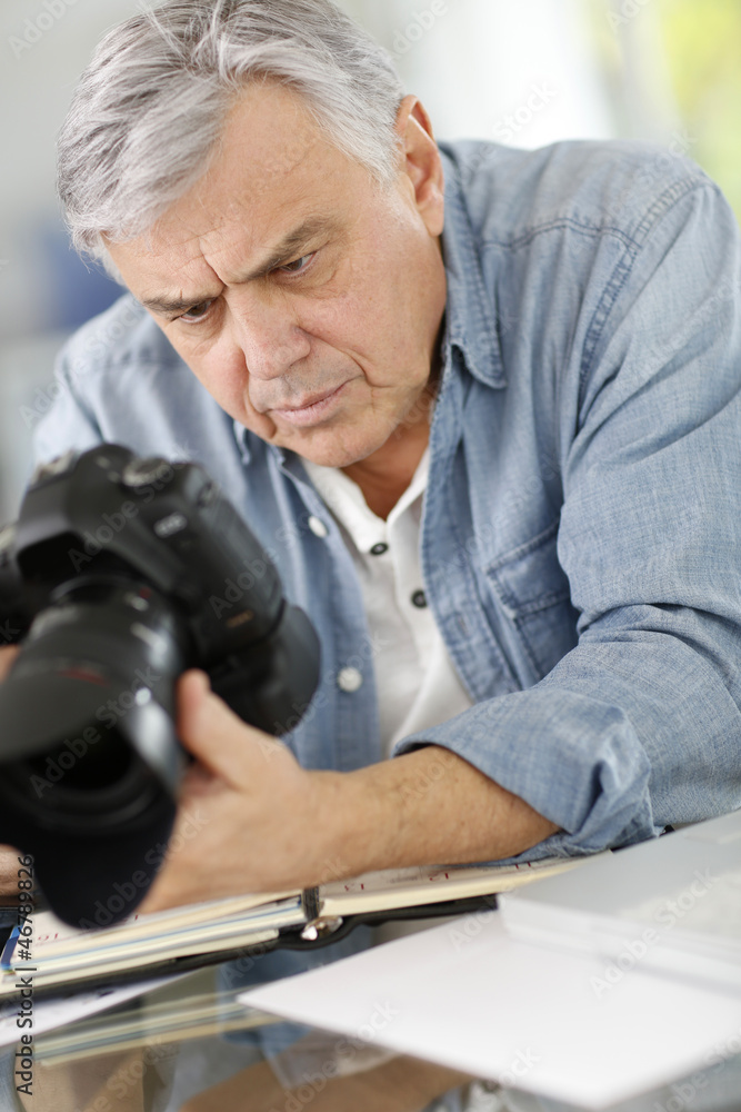 Photographer in office looking at camera screen Photographer in office looking at camera screen