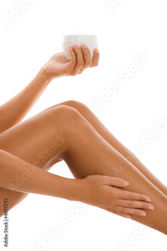 Woman applying body lotion on leg