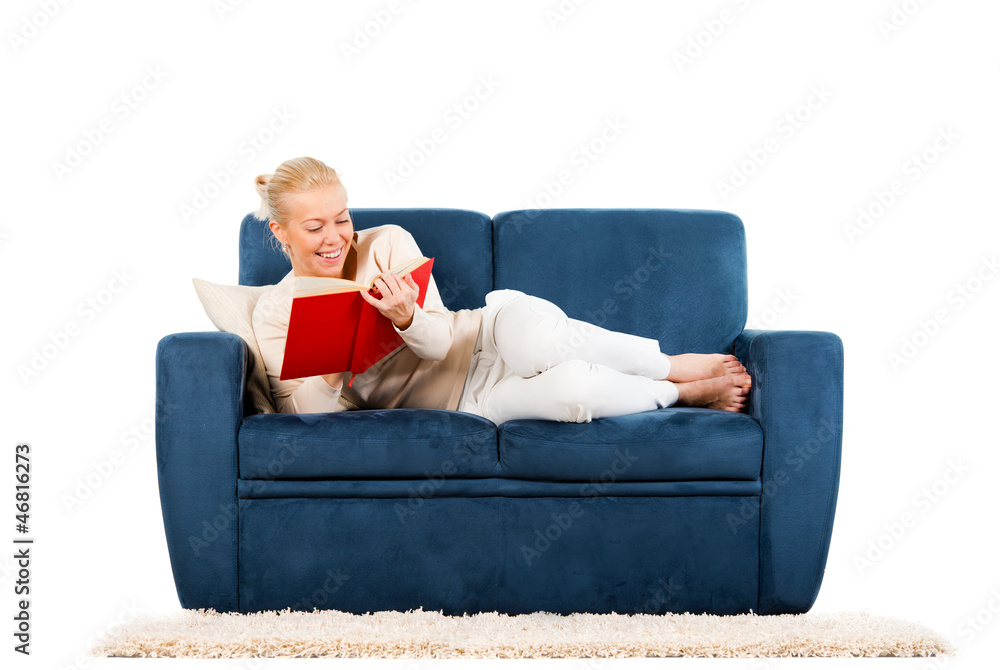 Young woman lying on a sofa reading a book
