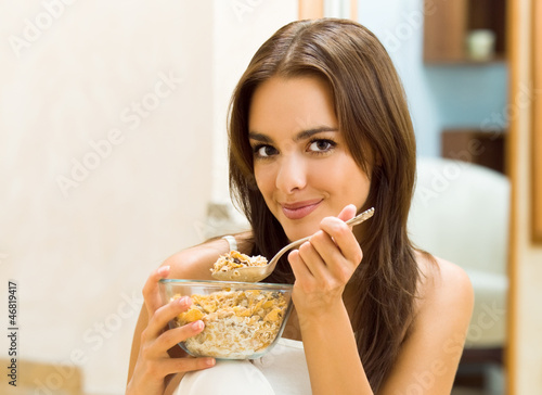Young woman eating cereal muslin (flakes)