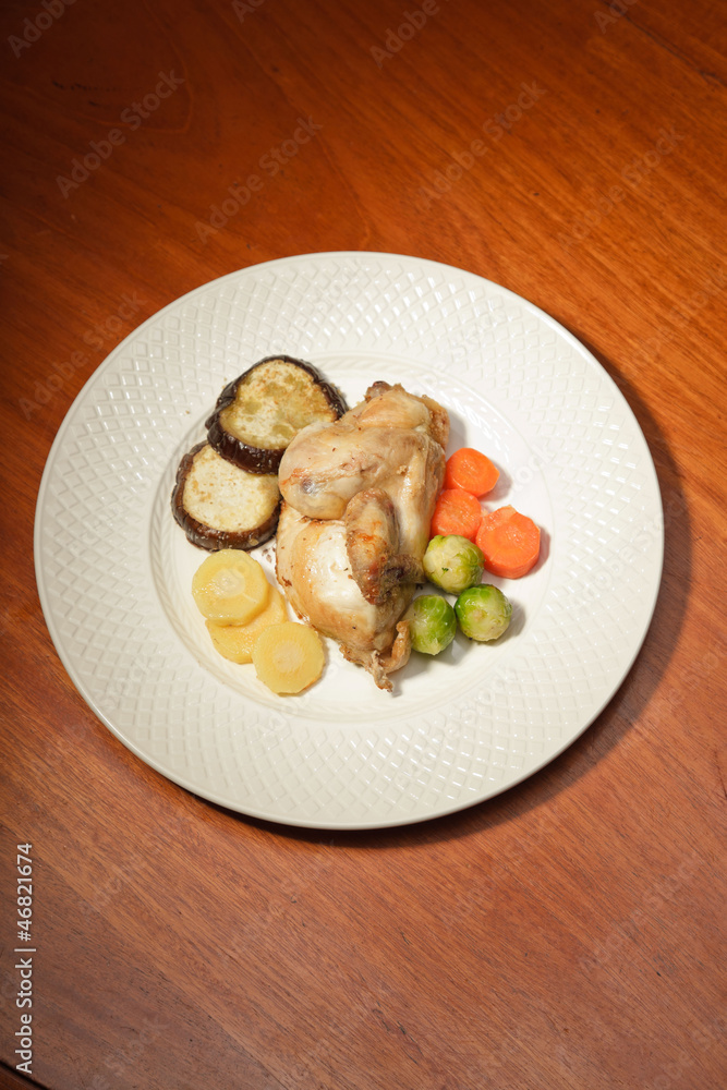 Dinner of vegetables and chicken on a plate and wooden table. Dinner of vegetables and chicken on a plate and wooden table.