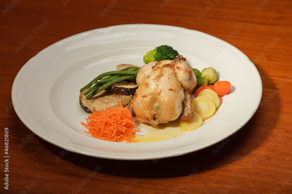 Dinner of vegetables and chicken on a plate and wooden table.