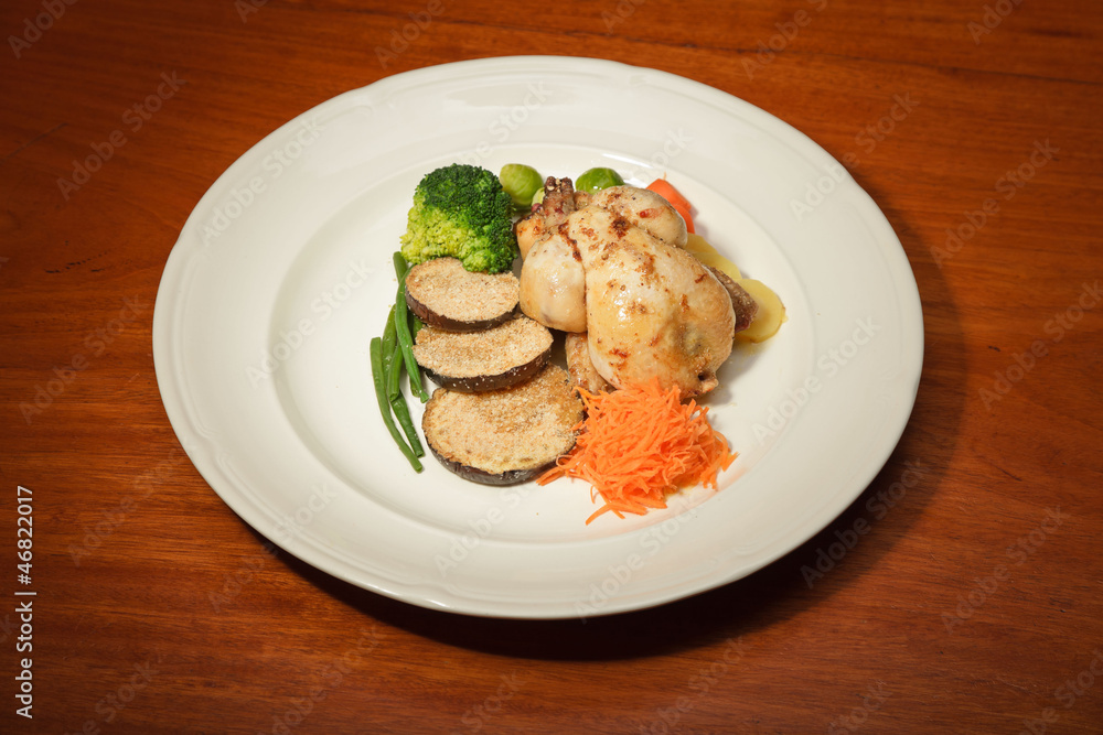 Dinner of vegetables and chicken on a plate and wooden table. Dinner of vegetables and chicken on a plate and wooden table.