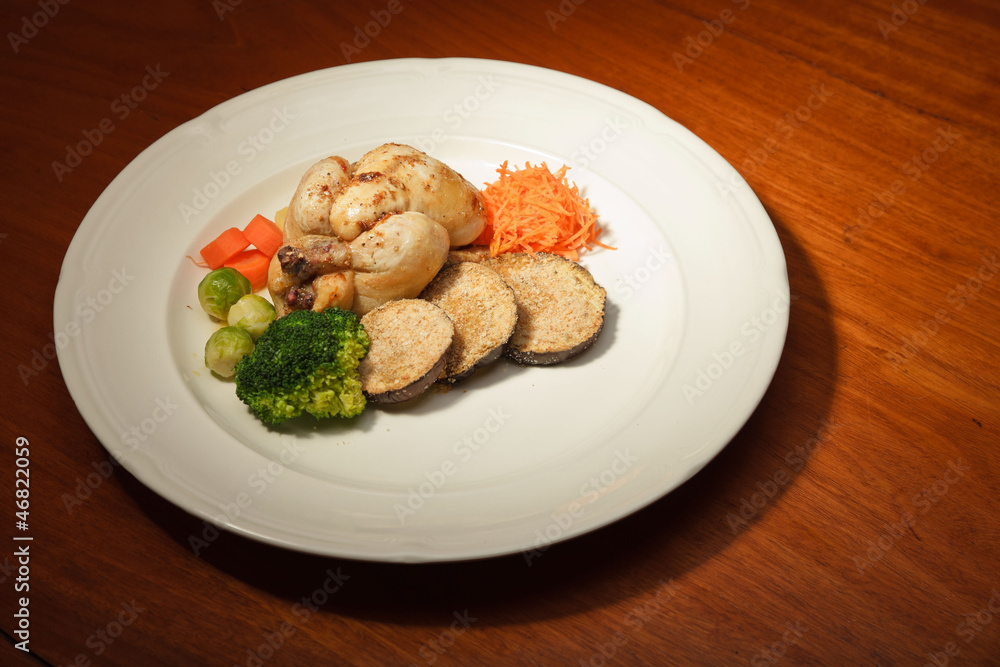 Dinner of vegetables and chicken on a plate and wooden table. Dinner of vegetables and chicken on a plate and wooden table.