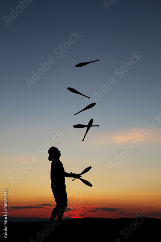 circus artist juggling with seven juggling clubs in sunset